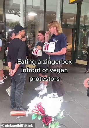 'do you want a bite?' two men taunt vegan protesters by eating a kfc zinger box in front of them
